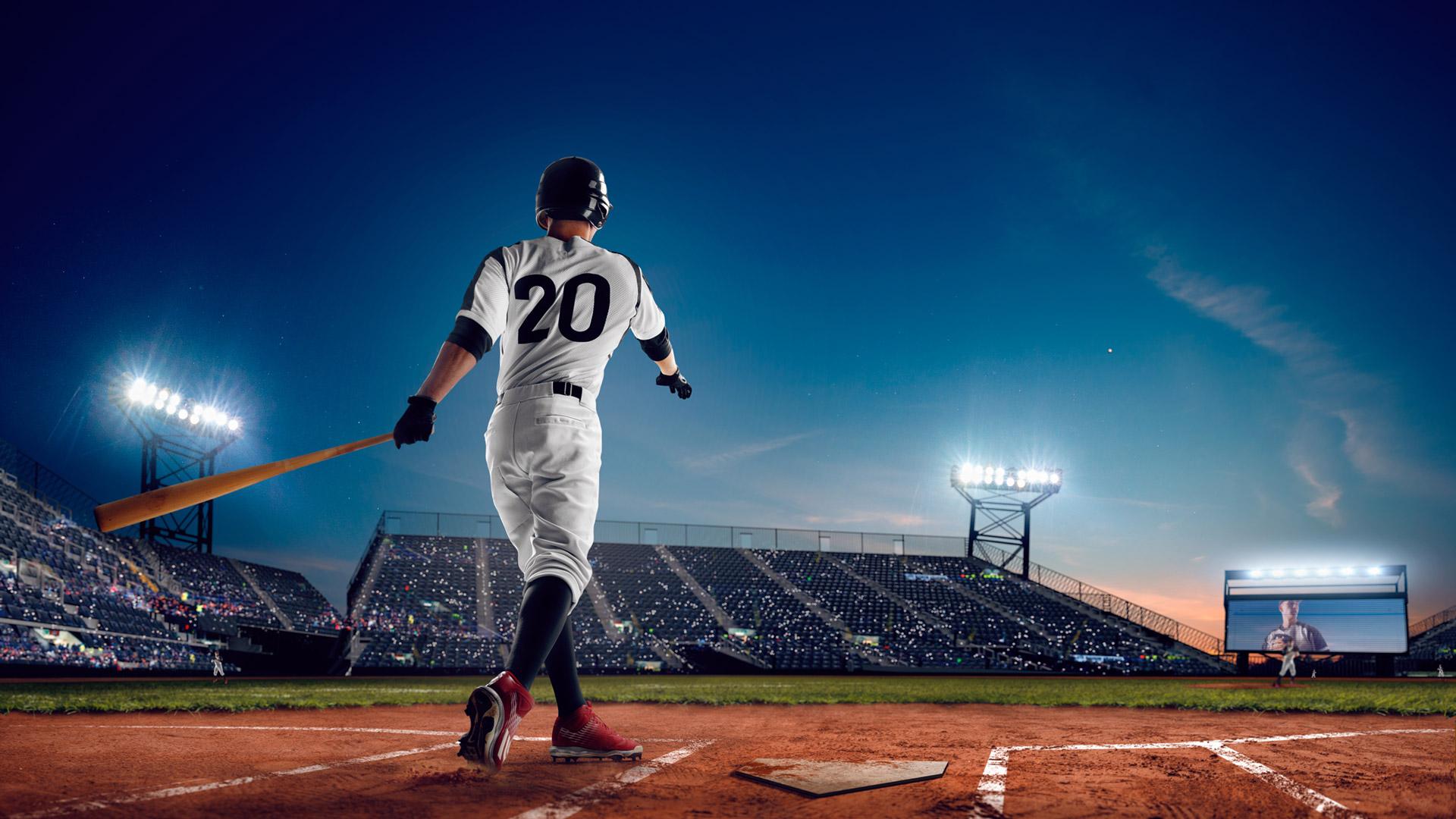 Baseball player hits the ball during an evening game.
