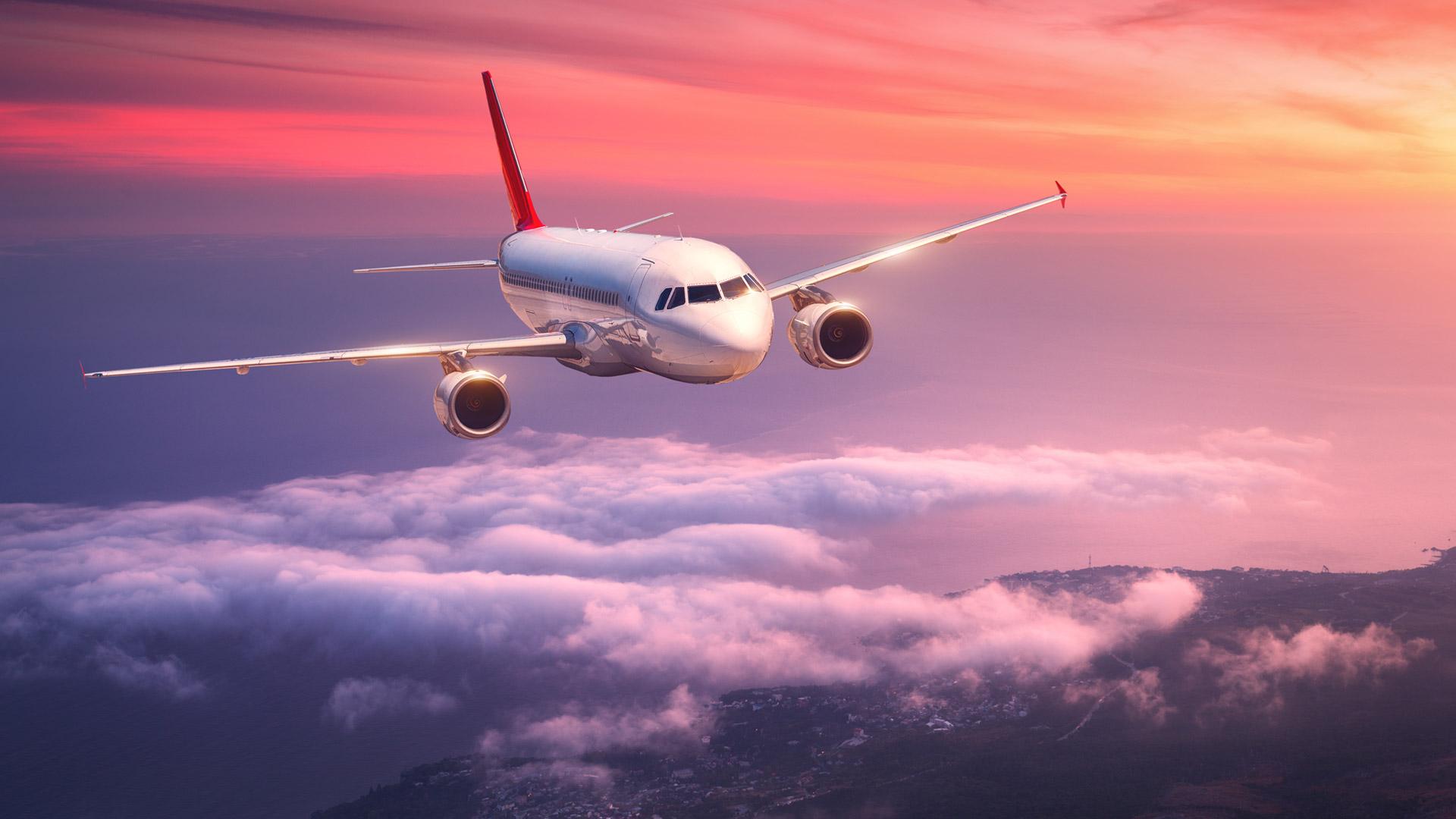Airplane flying above the clouds during a spectacular sunset.