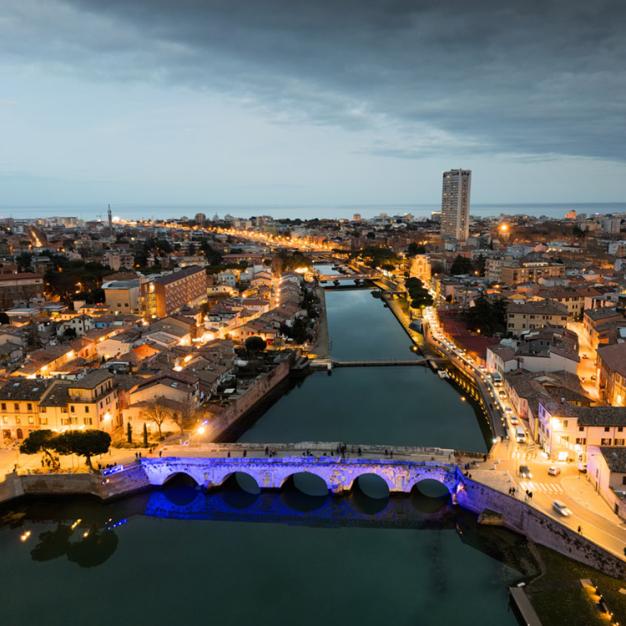 Night view of a city with an illuminated bridge and a river.