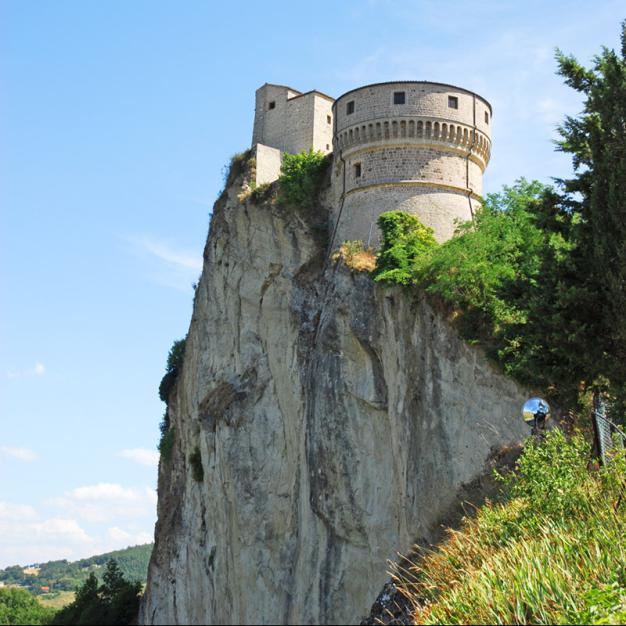 Medieval castle on a cliff with panoramic views and blue sky.
