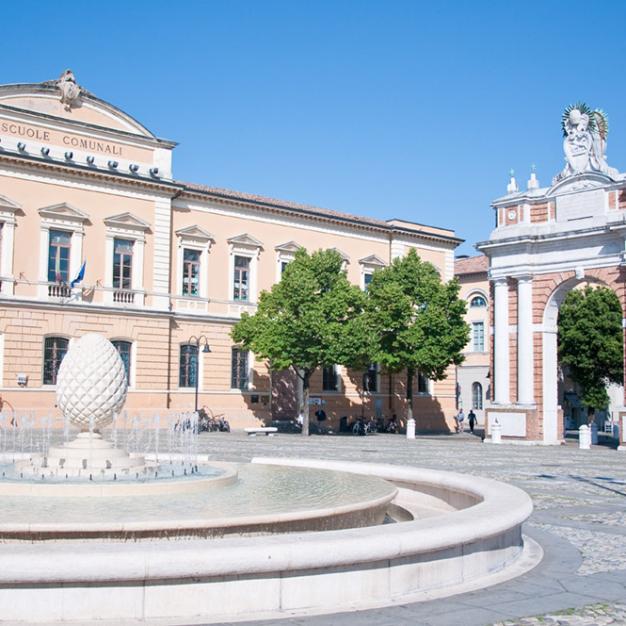 Fountain and arch near the Municipal Schools in a sunny square.