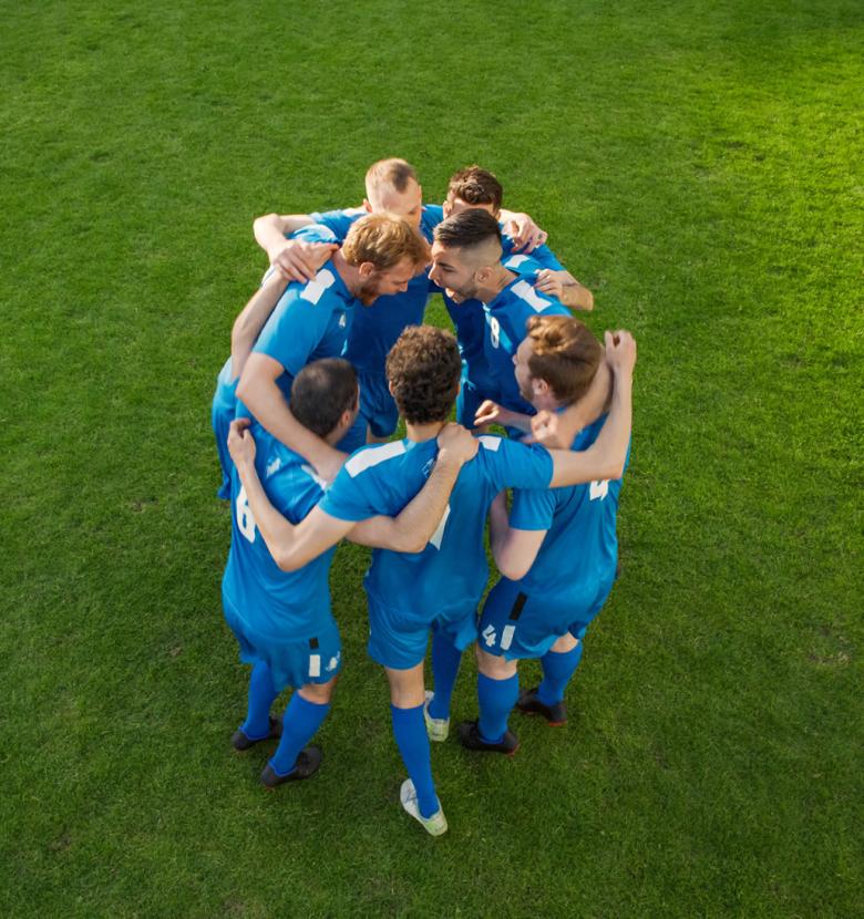 Soccer team huddled in a circle for encouragement on the field.